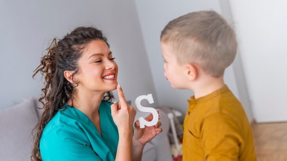 Young boy doing speech exercises with special education needs teacher