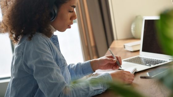 Young woman sits at desk in from of computer studying