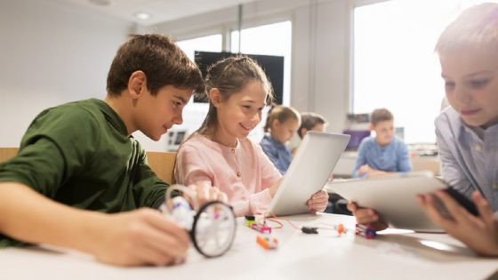 Young children sitting in classroom on digital devices