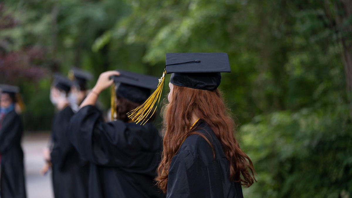 University graduates in gown and graduation hat waiting in line to receive their degree